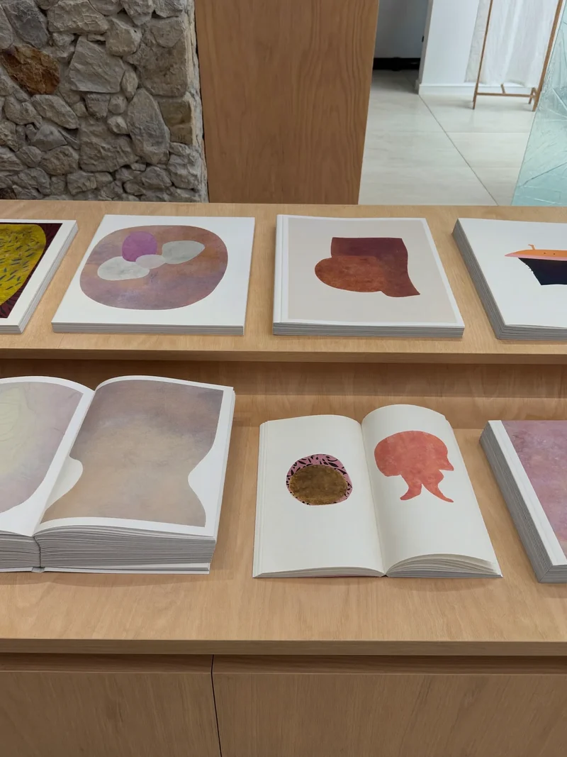 Illustration aufgeschlagener Kunstbände mit abstrakten Farbformen auf einem Schrägregal