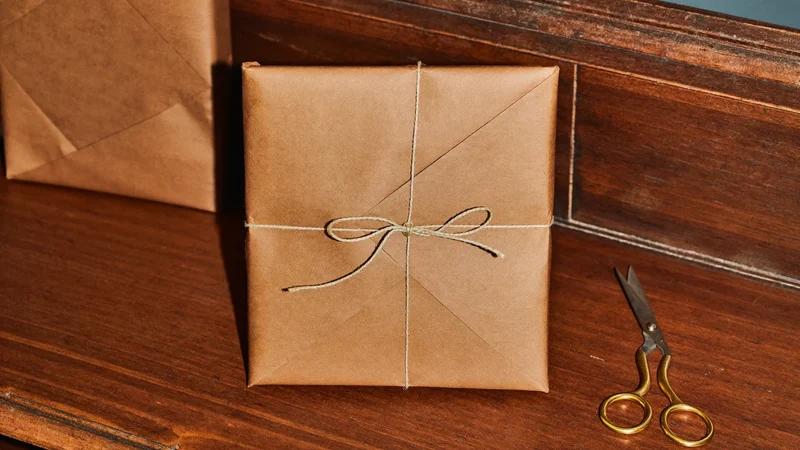 Illustration eines Ladentresens mit Packpapier, Schnur und einem Buch als Geschenk